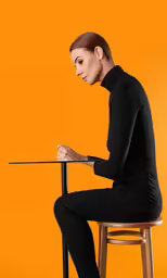 woman sitting on a stool writing with a paper