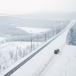 an over pass train traveling down tracks in the winter