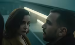 a man and woman looking at each other in a subway station