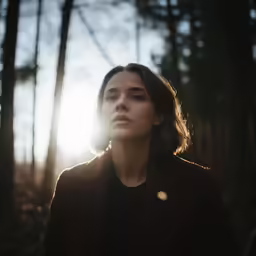 a woman standing in a forest looking into the distance