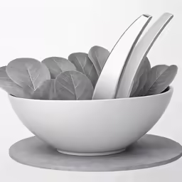 a white bowl filled with metal leaf sculptures