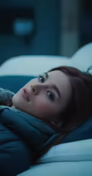 the girl is laying down on a sofa with her stuffed dog