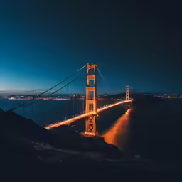 an illuminated bridge spanning over the water at night