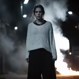 woman standing next to fire with smoke behind her