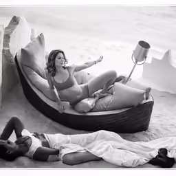 two women are laying on a beach towel and having fun