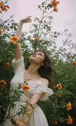a woman in a white dress touching a tree branch with an open hand