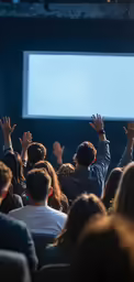 several people raising their hands to be shown a large screen
