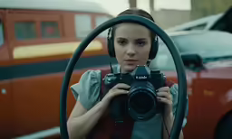girl looking through large hoop with a camera behind her