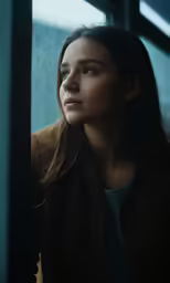 a young woman looks out of the window