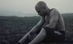 a man sitting on the ground and touching his knees