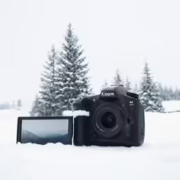 a camera sitting in the snow, with trees in the background