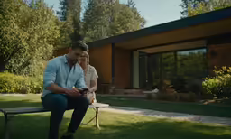 the man is sitting on the bench talking on his phone