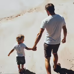 a man and a child walking along a beach