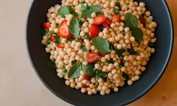 a bowl of corn and tomatoes with leaves