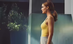 a woman in a yellow top is standing near a tree