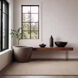 a modern room has two large windows and a small table with a vase
