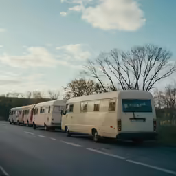 three motorhomes line up in front of a row on the street