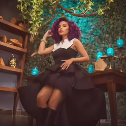 the model is sitting on a chair with an elaborate wig