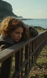 a young woman leaning on the rail over the ocean