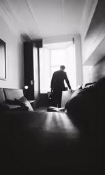 a black and white photo of a man standing next to the window