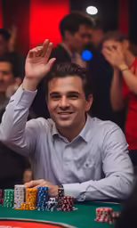 a man smiles while holding up his hand at the poker table