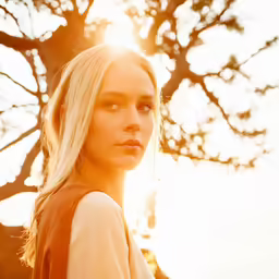 a young woman standing under a tree with her sun behind her