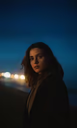 a person standing next to the water at night