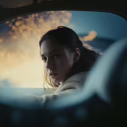 a young woman is sitting in the passenger side mirror