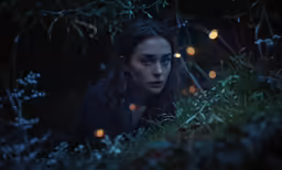 woman in forest with lite eyes staring into the camera