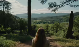 a woman stands alone on a dirt road