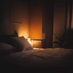 a bed with white pillows next to a night light