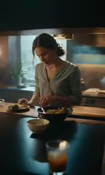 a woman preparing food in a kitchen next to a bowl