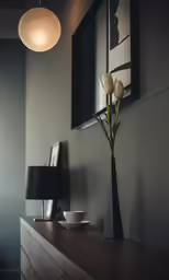 a vase with tulips sits on a dresser by a mirror