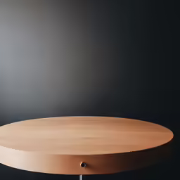 an empty round wooden table sitting against a black wall