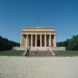 a building with columns and steps, on dirt ground