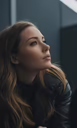 the woman in the leather jacket is looking into the distance