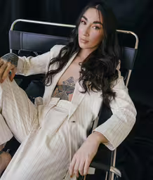 a woman is sitting in a chair wearing white,a women who is dressed like she