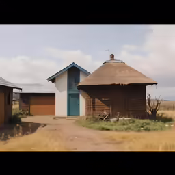 a dirt road passes by a small cabin on stilts