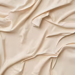 a bed with a cream fabric with a wrinkled back