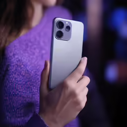 a woman holding up her apple phone in front of her