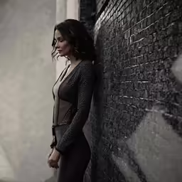 a woman standing against a wall wearing a dress