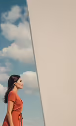 a woman in a short orange dress near a wall