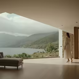 a woman standing next to a large window in front of a lake