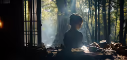 woman sitting on the ground outside of a window in the forest