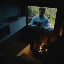 a man standing in front of a fire place holding a camera