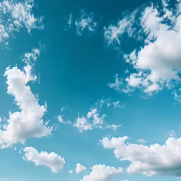a large open field filled with grass under a blue sky