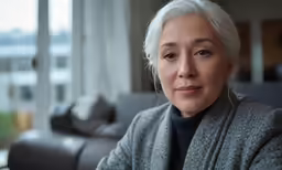 an older woman wearing ear piercings on a couch