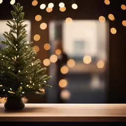 small lit christmas tree sitting in front of blurred wall