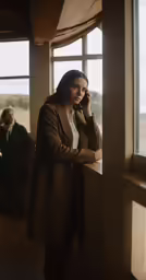 a woman looking out a window and holding a cell phone to her ear