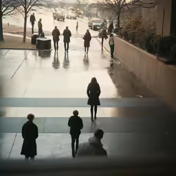 a group of people are walking down a sidewalk with cars and buildings